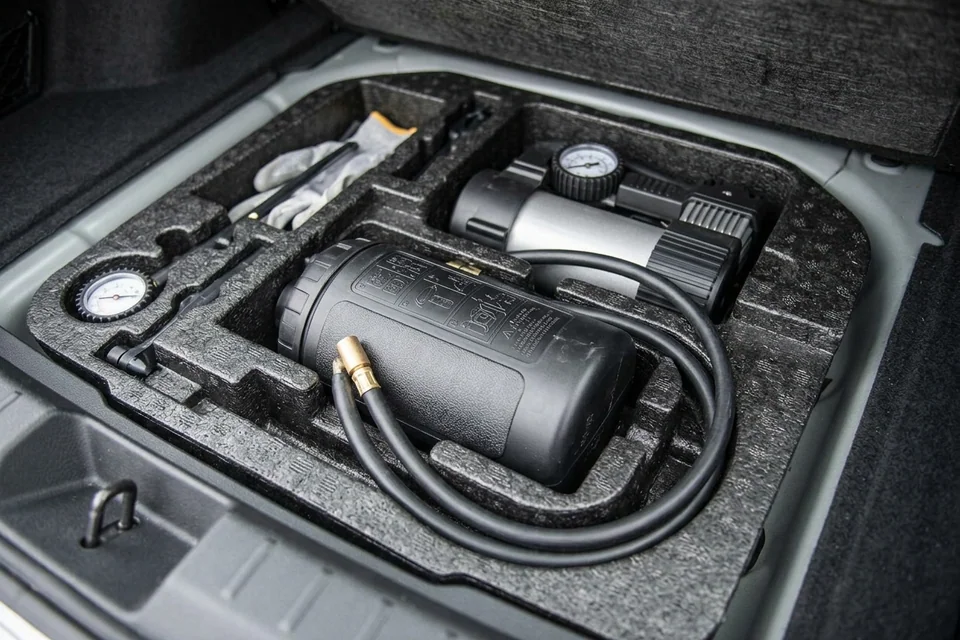 Factory tire inflator and sealant kit in the foam tray under a car trunk floor